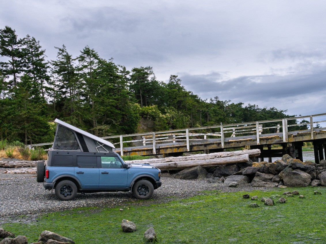 Bronco with Ursa Minor Camper parked by beach